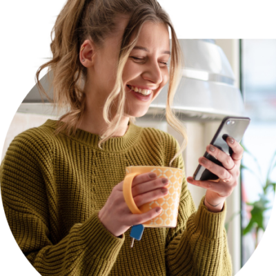 oiung woman smiling at phone drinking tea